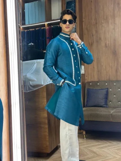 A different angle of the teal blue layered kurta, showing how the garment moves with the wearer. The asymmetrical cut of the inner kurta adds a contemporary edge.