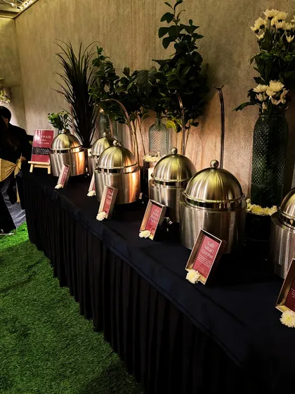 A modern and elegant Indian buffet line with sleek, stainless steel chafing dishes. This setup, complete with greenery and soft lighting, shows our ability to adapt our presentation to any event style.
