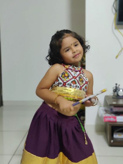 A cute pose from our little client in her purple and gold Garba outfit, showing off her dandiya sticks.