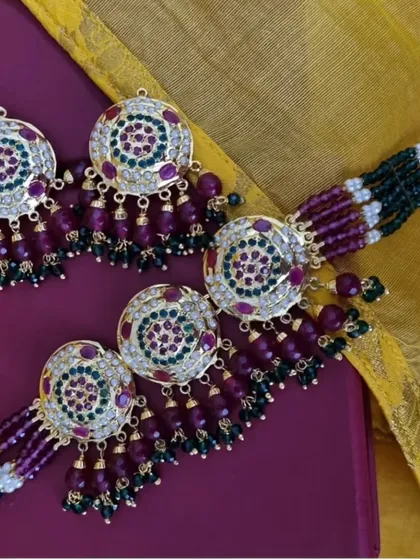 The 'रुकमणि' (Rukmani) Jadau set, featuring circular motifs with rich purple and green stones. This is a vibrant and festive piece, perfect for adding a splash of colour.