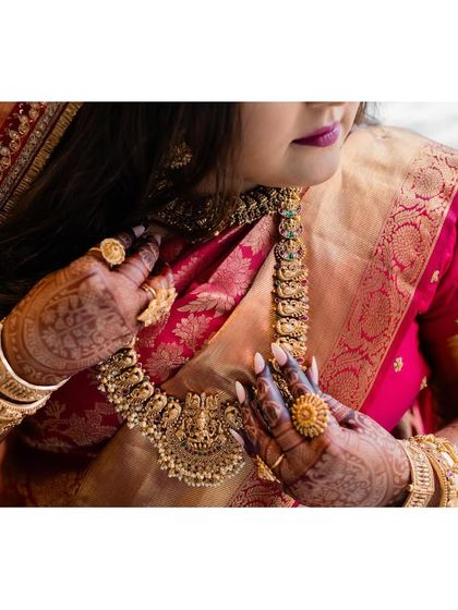 A detail shot of the bride's jewelry. The layered gold necklaces and statement rings are characteristic of a traditional Mallu bride, adding richness and grandeur to her look.
