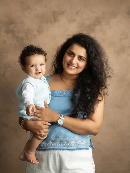 A beautiful, classic portrait of a mother and her smiling baby looking directly at the camera. This is a timeless shot that every family cherishes.