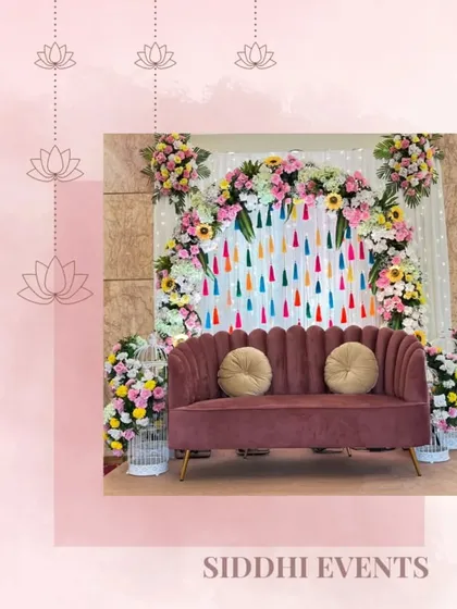 A playful and colorful stage with a backdrop of hanging tassels and a frame of sunflowers and other bright blooms, perfect for a lively Mehendi or Haldi event.