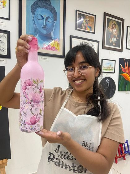A participant proudly holds up her finished decoupage bottle. The workshop is a great introduction to the world of crafting and upcycling.