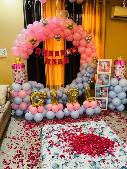 Here you can see the welcome home decoration set up in a bedroom. The bed is covered with rose petals, and the balloon arch with "GIRL" foils creates a festive atmosphere for the new mother and baby.