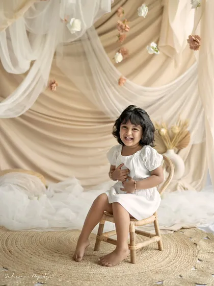 A little girl laughing with delight in our beautiful, draped studio setup.