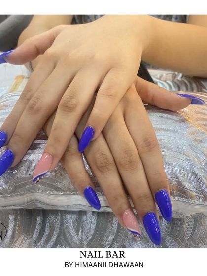 A bold and vibrant cobalt blue manicure, with some nails featuring a negative space design.
