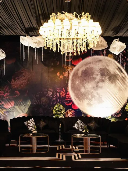 Thematic decor can transport guests to another world. For this celestial-themed sangeet, I created a cozy lounge area under a giant, glowing moon, set against a dark floral backdrop for a touch of moody romance.