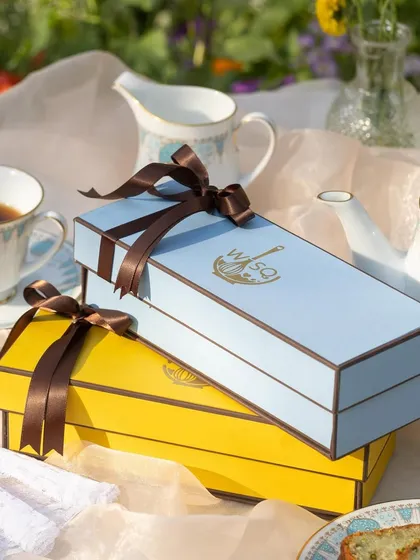 My signature gift boxes, available in vibrant yellow and serene blue, are designed to make your present feel special. Each is tied with a satin ribbon, ready for any occasion.