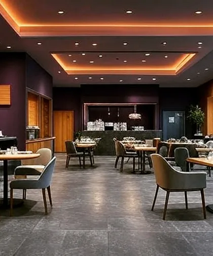 A spacious restaurant interior with a sophisticated color scheme of deep purple and wood. The coffered ceiling with cove lighting adds a touch of elegance and defines the different dining zones.