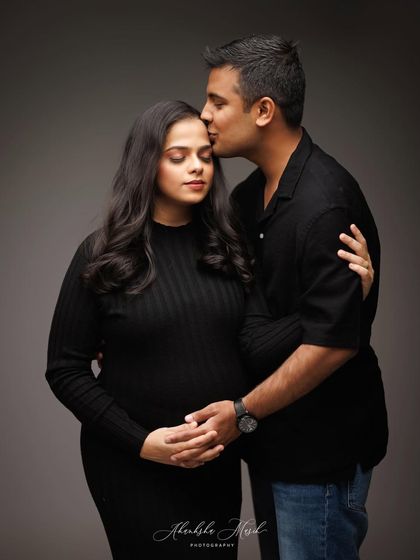 A classic and intimate maternity pose, captured in a timeless black and white style that highlights the couple's deep connection.