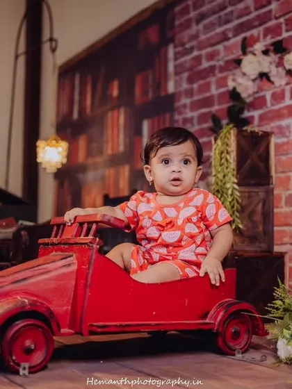 A creative indoor baby photoshoot featuring a fun, vintage-inspired setup with a miniature car and a library backdrop. These themed sessions are designed to be playful and capture your baby's curiosity.