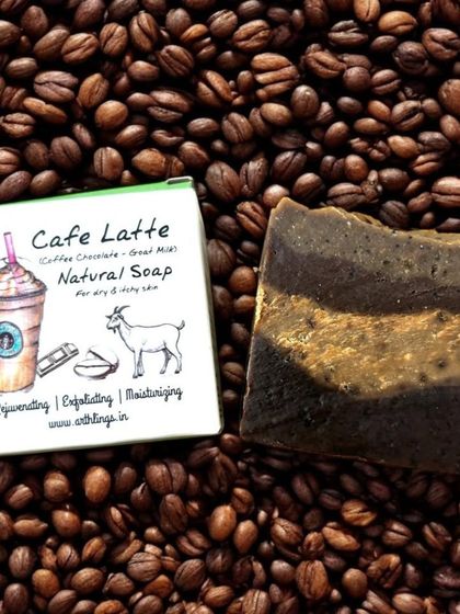Our Café Latte Natural Soap resting on a bed of coffee beans. This bar combines the exfoliating power of coffee with the moisturizing properties of goat milk for a truly invigorating wash.