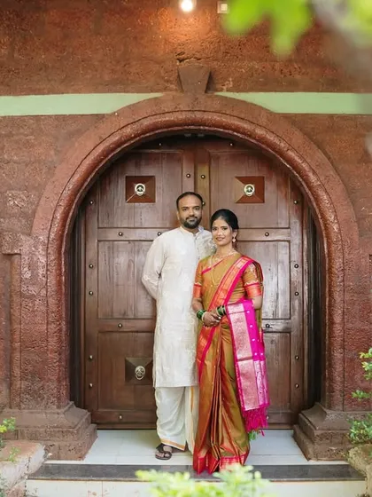 A wider view of the couple against the rustic stone and wood entrance. This environmental portrait tells a story of heritage and new beginnings.