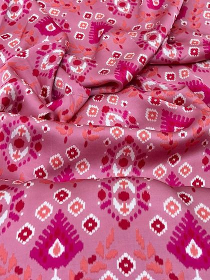 This pink modal satin with an ikat-style print is perfect for creating fun and vibrant outfits. Its soft, sleek texture is suitable for dresses, kurtas, and co-ord sets.