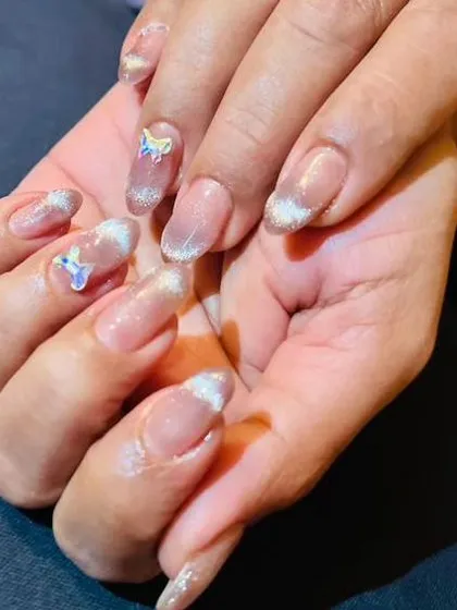 A whimsical design with a silver glitter French tip and cute unicorn charms on a sheer base.