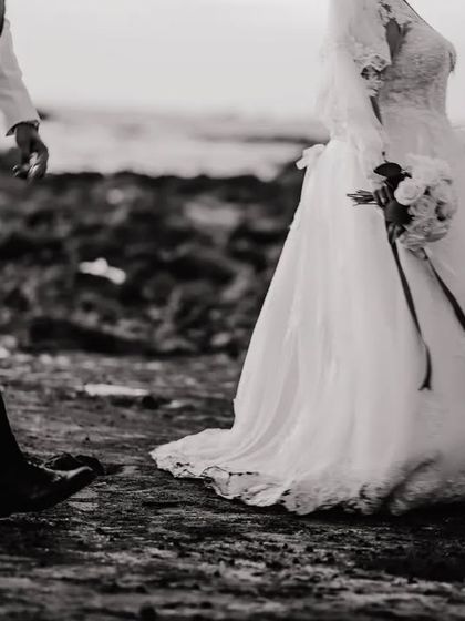 An artistic black and white shot focusing on the bride's gown and the groom's stride. This faceless portrait tells a story of movement and anticipation.