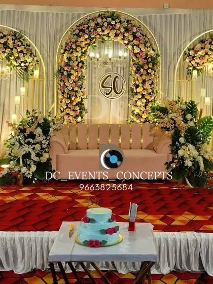 An elegant reception stage with three floral arches and hanging chandeliers. This symmetrical design provides a grand and classic backdrop, complete with a custom monogram for a personal touch.