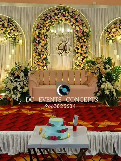 An elegant reception stage with three floral arches and hanging chandeliers. This symmetrical design provides a grand and classic backdrop, complete with a custom monogram for a personal touch.