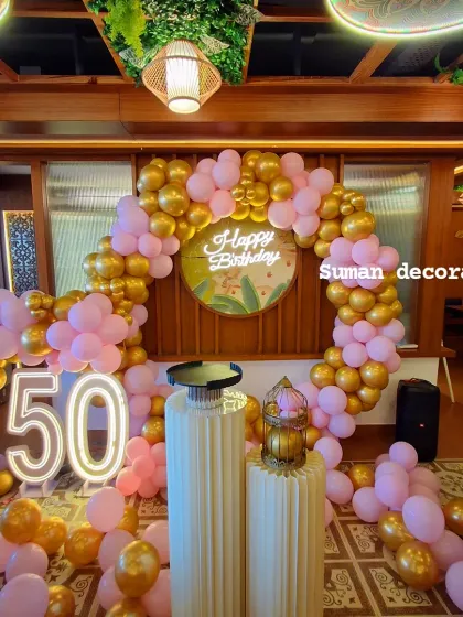 A different angle of the pink and gold 50th birthday setup, showing the full circular balloon arch and marquee numbers.
