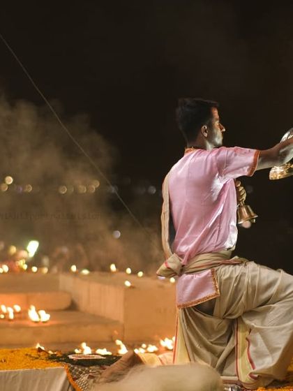 A priest performs the Ganga Aarti ritual at Dashashwamedh Ghat. This wide shot shows the synchronized movements and the diyas lighting up the steps of the ghat.