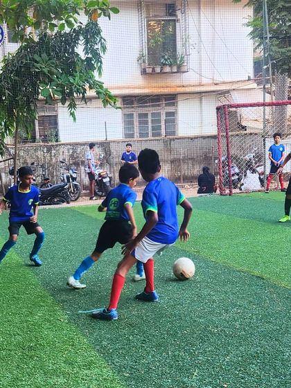 Two players vie for the ball during a football match. This image captures the competitive spirit and determination that we encourage in all our young athletes.