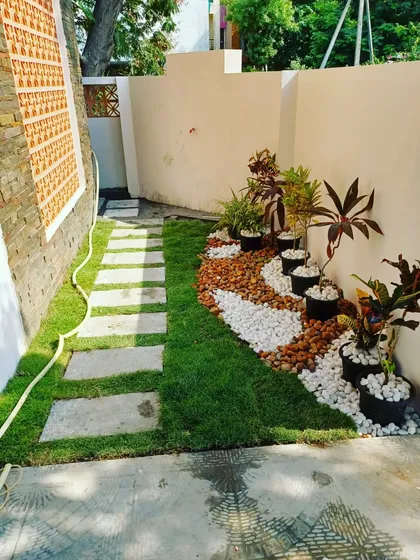 Even a small 100 sq. ft. area can be transformed into a beautiful garden. Here, I combined a neat lawn, a stone pathway, and a decorative pebble bed with potted plants to create a stunning and low-maintenance corner.
