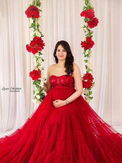 A full-length portrait on the floral swing, showcasing the incredible volume and color of the red tulle gown. This is a truly show-stopping setup.