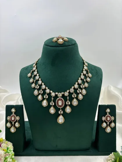 A necklace set with a unique design, featuring red stones and pearl drops.