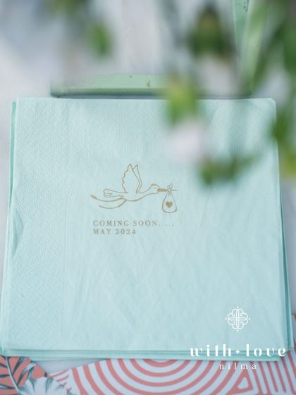 A custom-printed napkin from the baby shower, with a stork and the baby's due date.