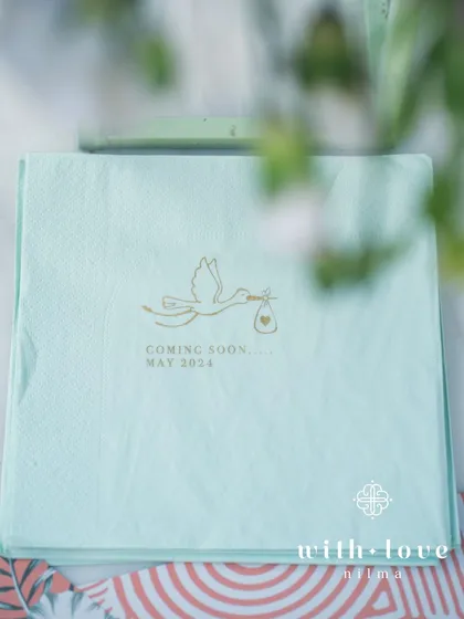 A custom-printed napkin from the baby shower, with a stork and the baby's due date.