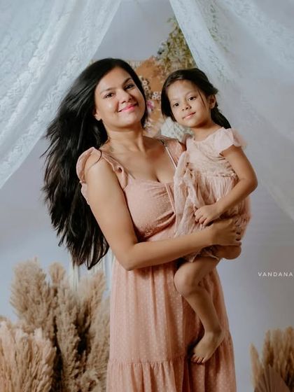 This portrait captures the mother's beautiful smile as she holds her daughter. The soft lighting and boho decor add to the warm and gentle feel of the image.