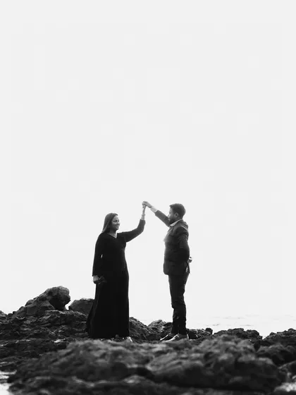 A wide, atmospheric shot in black and white. The couple looks small against the vast, empty backdrop, creating a feeling of intimacy and a world of their own.