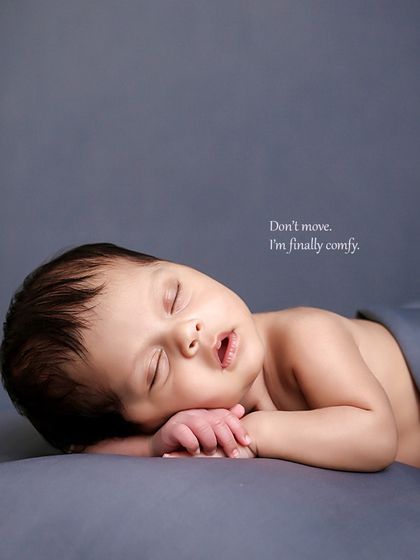 A simple and serene side-lying pose on a neutral grey backdrop. This pose highlights the baby's delicate profile and tiny hands, capturing them in a state of deep comfort.