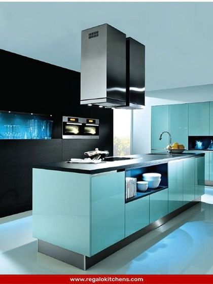 This futuristic kitchen design uses a vibrant aqua blue with high-gloss finishes and integrated blue lighting. The island includes open shelving for display, while the built-in aquarium wall adds a unique, custom touch of luxury.