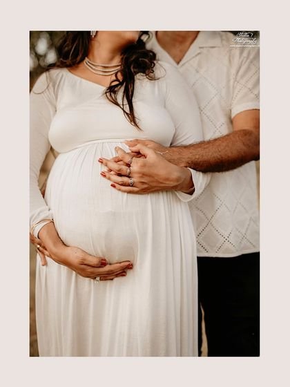 A detailed shot focusing on the couple's hands intertwined over the baby bump. This emphasizes the partnership and shared journey of pregnancy.