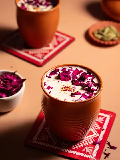 A beautifully styled glass of Thandai, garnished with rose petals and saffron. This image captures the festive and traditional spirit of Holi.