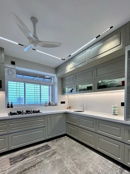 A classic vintage-inspired kitchen in a soft grey finish. The design includes shaker-style cabinets, under-cabinet lighting, and a marble-patterned floor for a timeless look.