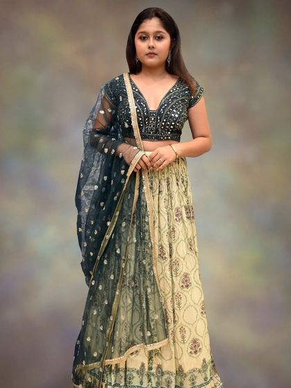 The full view of the bottle green and pastel yellow lehenga, showing the beautiful contrast and the delicate net dupatta.