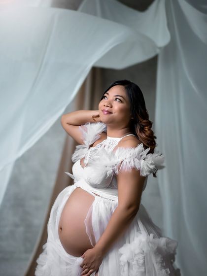 A close-up of the mother-to-be looking up, filled with hope and wonder. The delicate white gown adds to the heavenly feel.