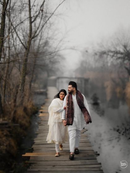 Walking hand-in-hand across a rustic wooden bridge in Kashmir. The misty, atmospheric setting creates a beautifully romantic and timeless feel for this pre-wedding portrait, highlighting the couple's journey together.