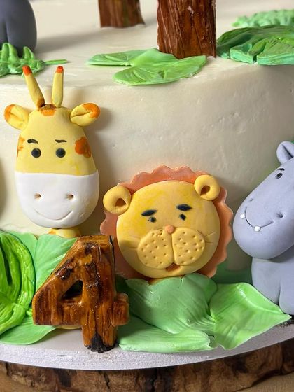 A close-up on the cute, handcrafted animal faces on the animal farm cake. Look at the friendly lion, hippo, and giraffe, all ready to party.