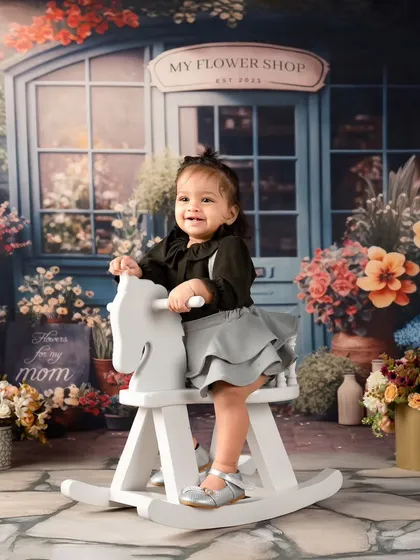A first birthday shoot set against a charming flower shop backdrop. This little girl's smile is as bright as the flowers around her.