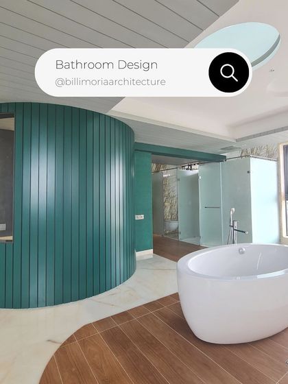 A unique bathroom design featuring a curved, teal-colored partition that separates the vanity area from the freestanding tub. The mix of wood-look tiles and marble flooring adds texture and visual interest.