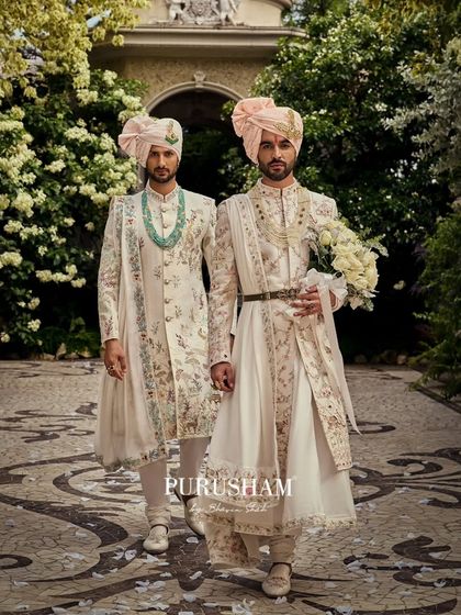 This is how I envision a modern royal wedding. Two grooms, walking side-by-side in coordinated yet distinct floral sherwanis, embodying grace and heritage. The soft pastel turbans and white roses complete the vision.