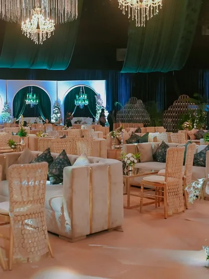 A view of the guest seating area, featuring a mix of plush velvet sofas and elegant chairs. The decor is tied together with custom-printed cushions and classic white and gold furniture.
