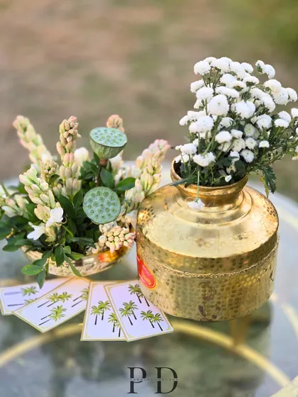 A beautiful tablescape detail featuring brass vases, fresh tuberose, and lotus pods, along with custom-printed cards.