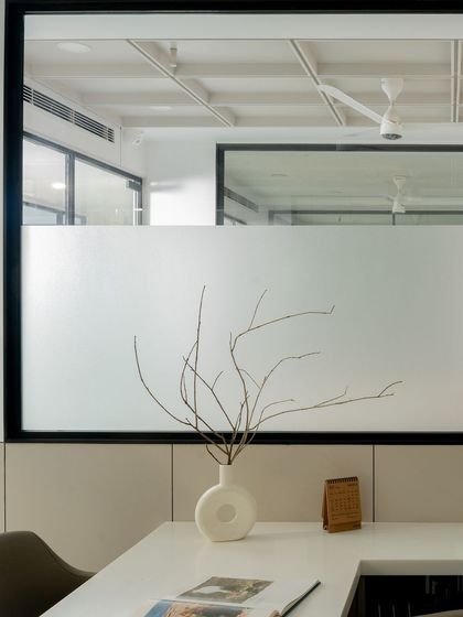 A detail shot showing the frosted glass partition, which provides privacy for the adjacent space while allowing light to pass through, maintaining the office's airy feel.