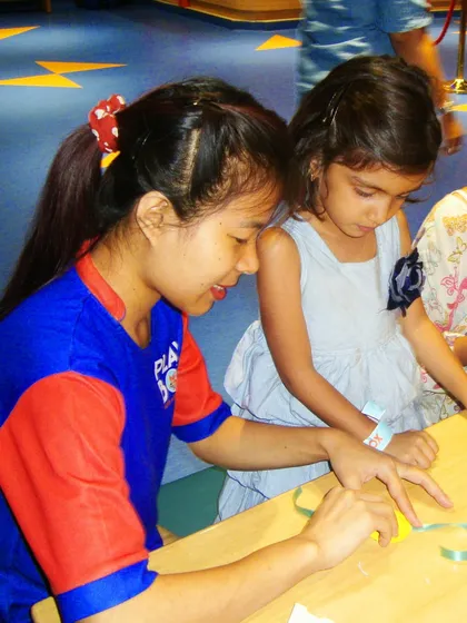 An instructor assists a young girl in making a beautiful rakhi during our craft workshop.
