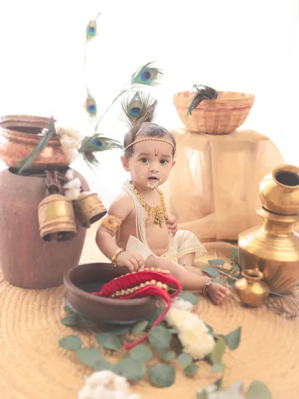 This high-key setup uses a bright white background to create a modern, fresh take on the traditional Krishna theme, making the colors of the props pop.